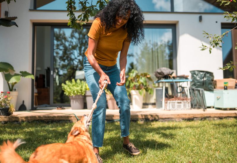 A woman plays tug with her dog outdoors, showing fun bonding and exercise in Frisco and Allen, TX